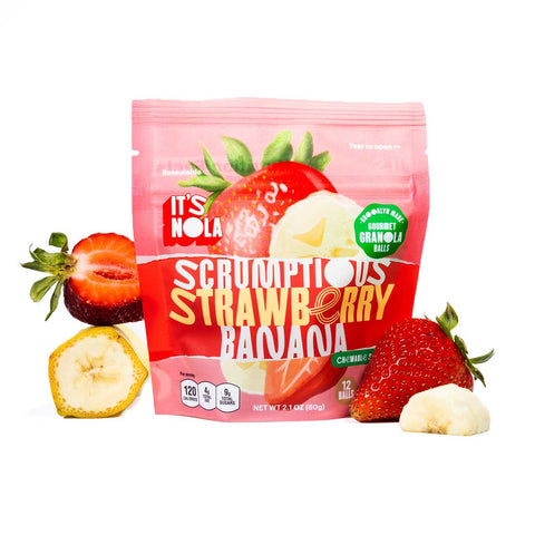 It's Nola Scrumptious Strawberry Banana is surrounded by a sliced strawberry and a sliced banana to the right of the package, and a slice of banana and a whole strawberry on the other side.